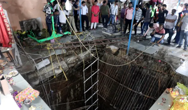 Njerëzit qëndrojnë rreth një strukture të ndërtuar mbi një pus të vjetër tempulli që u shemb të enjten. Fotografia: AP